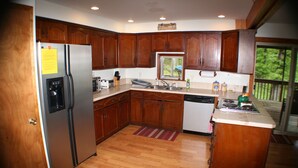 A kitchen with wooden cabinets, stainless steel appliances, and a window overlooking greenery. - 4-bedroom house overlooking Lake Norfork with AC comfort (Mountain Home)
