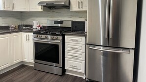 Une cuisine avec des armoires blanches, un réfrigérateur en acier inoxydable, une cuisinière et un four à micro-ondes.
