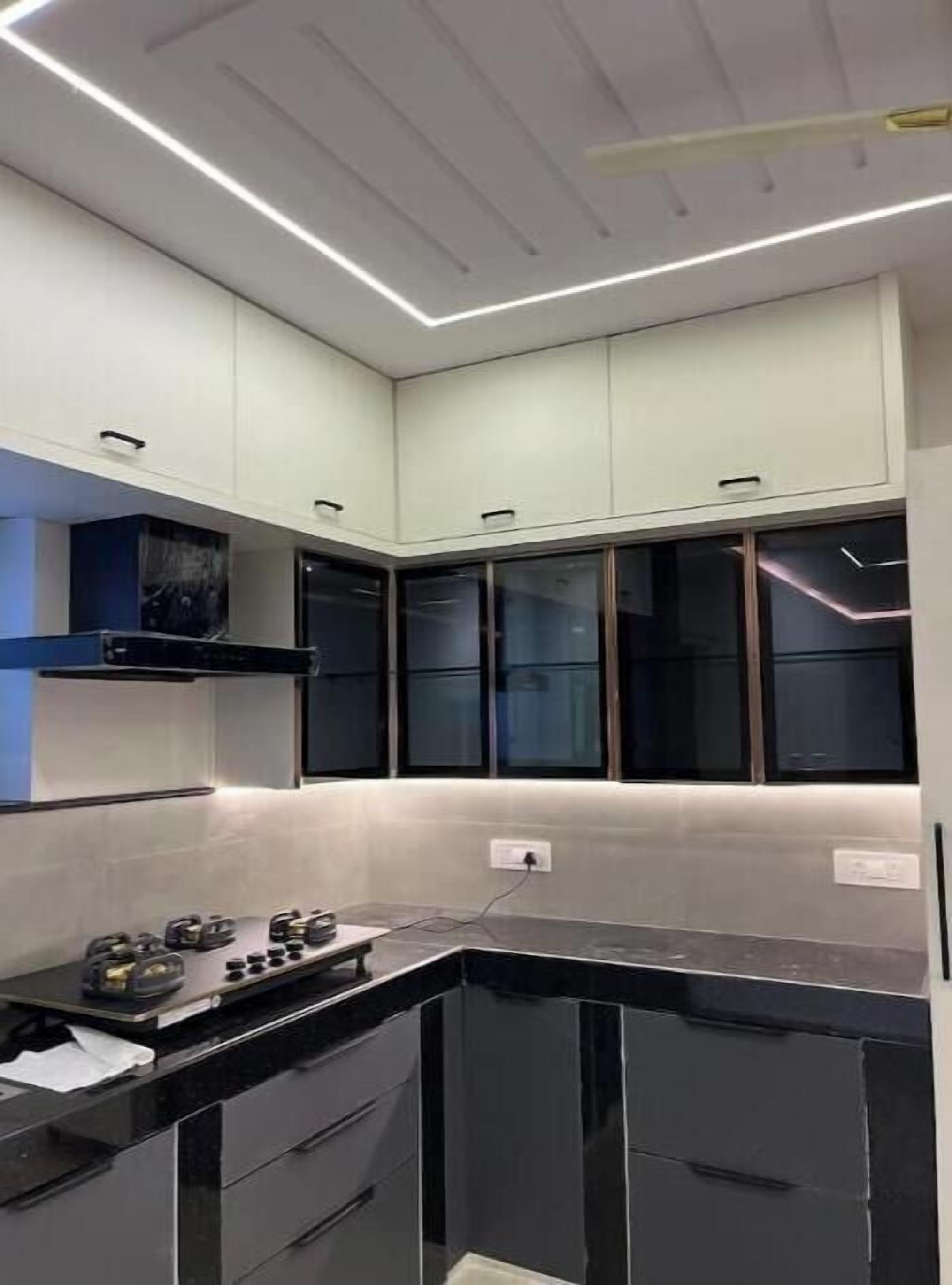 A modern kitchen with black countertops, white cabinets, and a built-in oven.