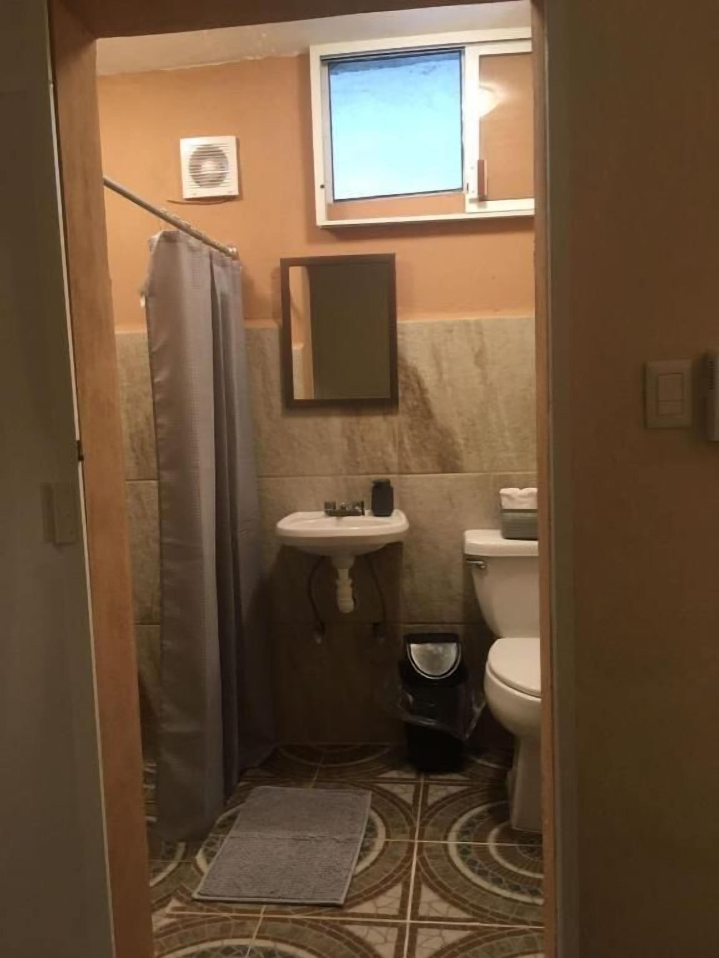 Un baño pequeño con ducha, lavabo e inodoro.