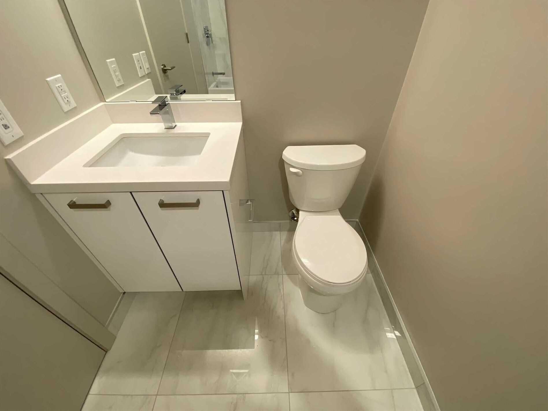 Un baño con lavabo blanco, espejo e inodoro.
