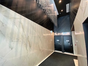 A modern interior with marble walls, a chandelier, and a neon sign.
