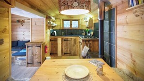 Interior de una cabaña de madera con cocina, comedor y una zona de estar acogedora.