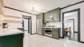 Una cocina moderna con una isla central, electrodomésticos integrados y un área de comedor visible a través de un vano abierto.