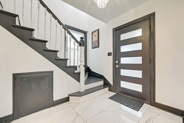 A staircase with white balusters, a dark door with frosted glass panels, and a marble floor. - Spacious 3-bedroom house in charming Houston with AC (Houston)