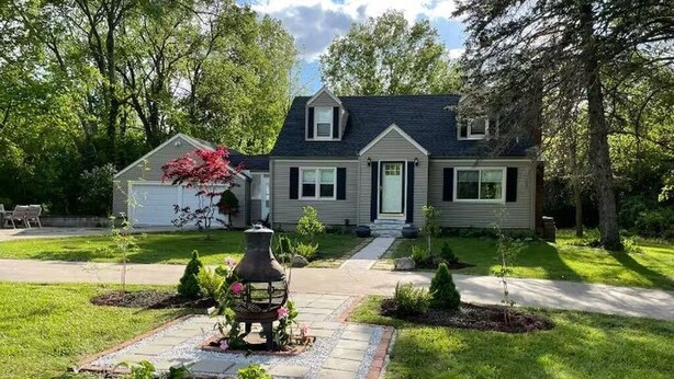 A two-story house with a front yard, a driveway, and a small garden area. - Immaculate 3 bedrooms and very private backyard with firepit. (Bloomfield)