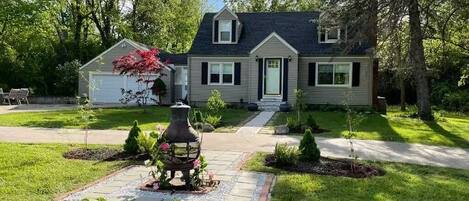 A two-story house with a front yard, a driveway, and a small garden area.