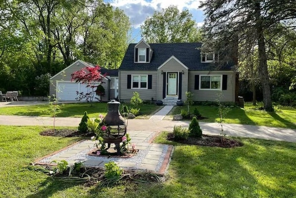 A two-story house with a front yard, a driveway, and a small garden area.