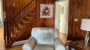 A room with a wooden staircase, a chair with a fur throw, and a wall-mounted artwork. - Immaculate 3 bedrooms and very private backyard with firepit. (Bloomfield)