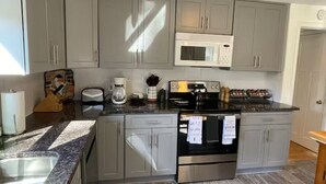 A kitchen with grey cabinets, a microwave, a coffee maker, a kettle, and a refrigerator. - Immaculate 3 bedrooms and very private backyard with firepit. (Bloomfield)