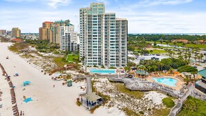Een hoog hotel met diverse verdiepingen, een zwembad en een ligging aan het strand.