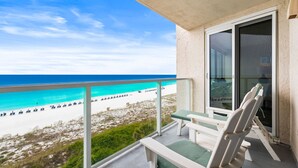 Een balkon met uitzicht op strand en zee.