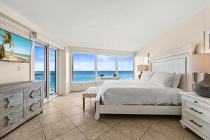 A bedroom with a large window, a bed, a nightstand, a dresser, and a television. - Stunning Gulf View and Beach Front Coastal Escape (Miramar Beach)
