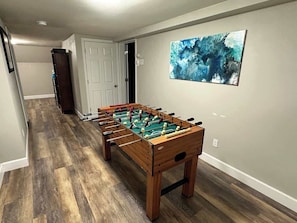 A hallway with a foosball table, a door, and a painting on the wall.