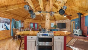 L’intérieur d’un chalet en bois comprend une cuisine équipée d’un poêle, d’un four et de casseroles suspendues.