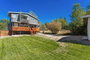 A two-story house with a garage, a wooden deck, and a well-maintained lawn. - Luxury Durango Retreat - Hot Tub, Views! (Durango)
