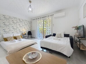 Ein Schlafzimmer mit zwei Betten, einem Holztisch, einem Fernseher und Blick ins Freie.