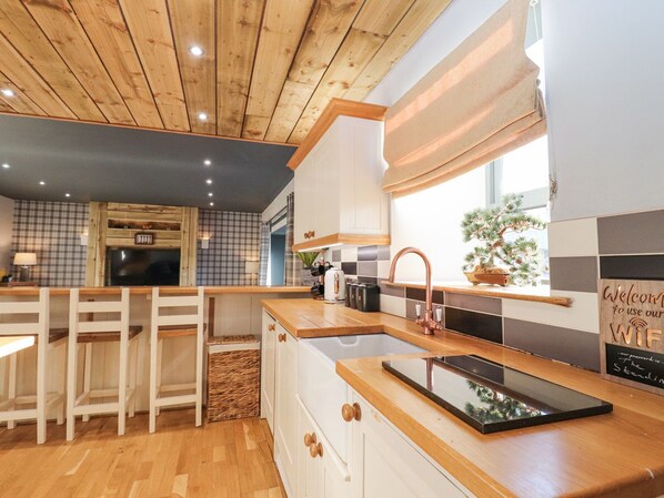 A modern kitchen with wooden cabinetry, a built-in island with a sink, and a window with a view of the outdoors.