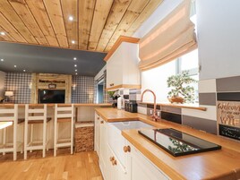 A modern kitchen with wooden cabinetry, a built-in island with a sink, and a window with a view of the outdoors.