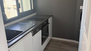 Ett kompakt kök med ett fönster, en diskmaskin och en ugn.