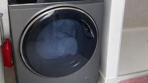 En bild som visar en tvättmaskin med frontmatning från framsidan, tagen i ett tvättrum.