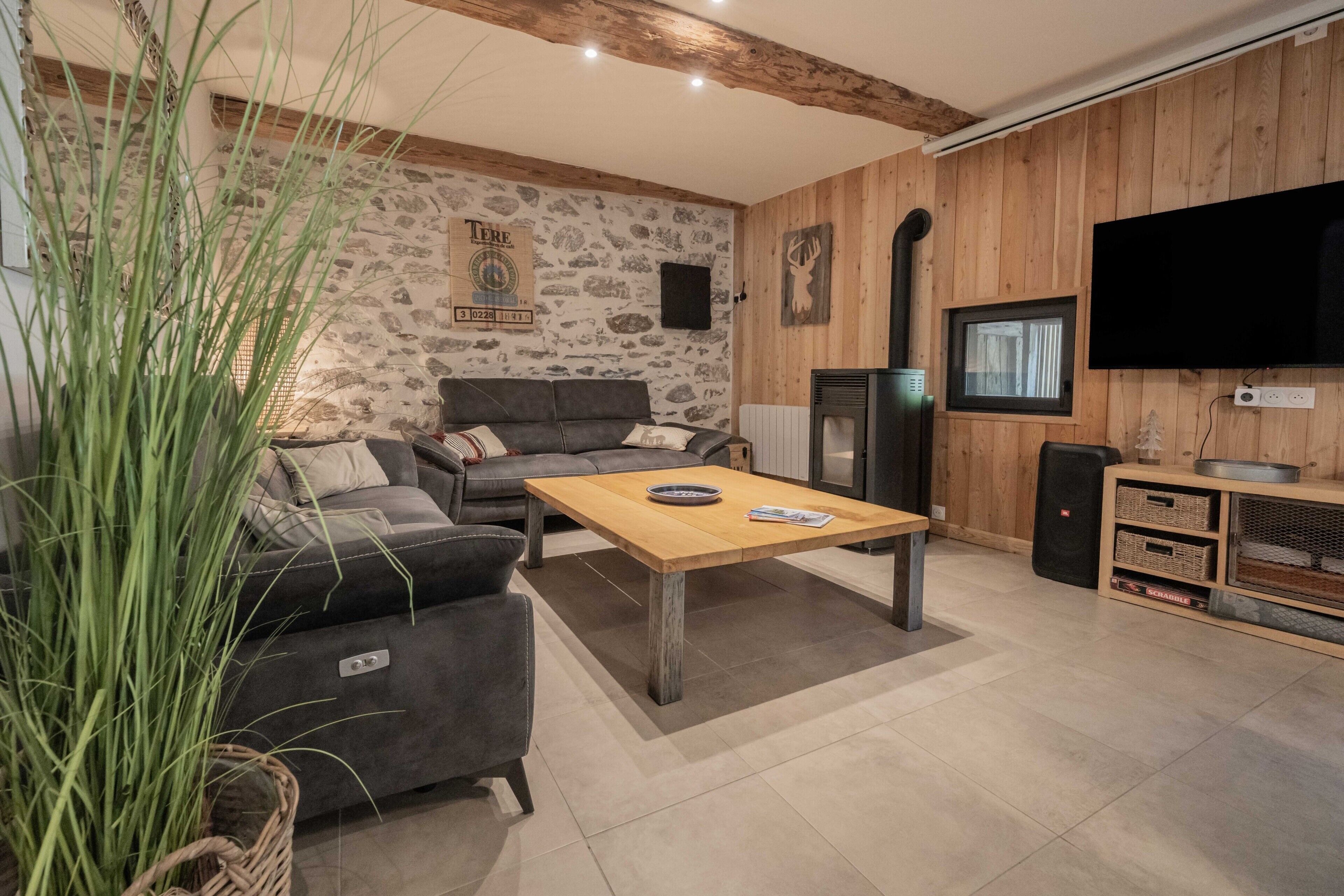 A living room with a sofa, a coffee table, a television, and a stone wall.