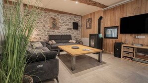 Ein Wohnzimmer mit einer Couch, einem Couchtisch, einem Fernseher und einer Steinwand.