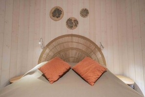 A bed with two pillows, a wicker headboard, and three wall-mounted leaf decorations. - Gite - La grange Tima: Spacious House with Mountain Views for Groups (Orgeix)