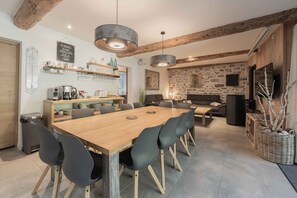 A modern kitchen with a wooden table, black chairs, and hanging pendant lights. - Gite - La grange Tima: Spacious House with Mountain Views for Groups (Orgeix)