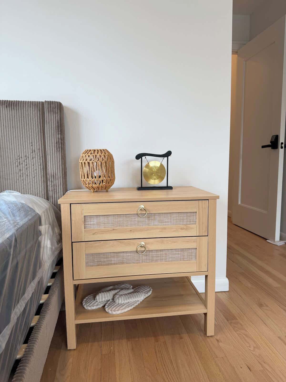 A wooden nightstand with drawers, a woven basket, and a wind chime.