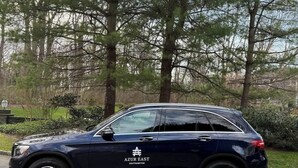 A dark blue SUV parked on a road with a logo on the side, surrounded by trees and greenery. - Pool Gym Biocharger Tennis Private bath All New BR (Southampton)