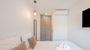 A hotel room with a bed, pillows, a hanging light fixture, a door, and an air conditioning unit. - 6P Apartment in a Citadelle /pool - Saint-tropez (Saint-Tropez)