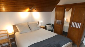 Une chambre à coucher comprenant un lit, des tables de chevet, une chaise, une armoire et un luminaire au plafond.
