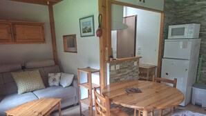 Ein gemütliches Wohnzimmer mit einem Holzesstisch, einer Couch und einem Kühlschrank.