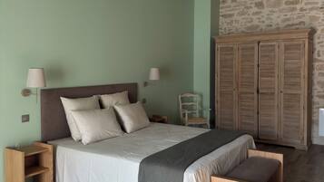Een slaapkamer met een bed, nachtkastjes, een stoel, een garderobe en een grote geweven tas.