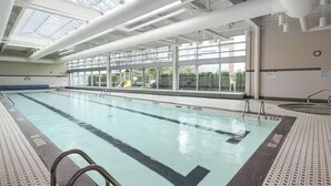 Ein Hallenbad mit klaren Glasdecken, einer Schwimmbahn und Blick auf Spielplätze im Freien.