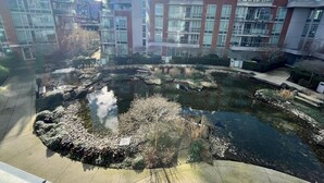 Ein moderner Gebäudekomplex mit einem zentralen Wasserspielplatz, umgeben von viel Grün.