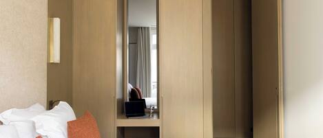 A hotel room with a bed, a desk with a laptop, and a wardrobe.