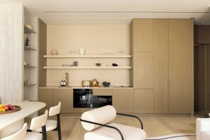 Eine moderne Küche mit Einbaugeräten, einer Essecke mit Stühlen und einem großen Schrank.