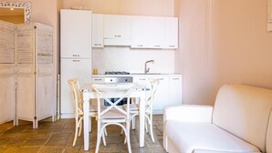 Une cuisine de taille réduite avec des meubles blancs, une table à manger avec des chaises et un canapé.