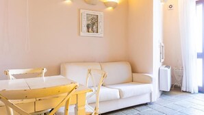 Une pièce avec un canapé blanc, une table en bois et un radiateur blanc.