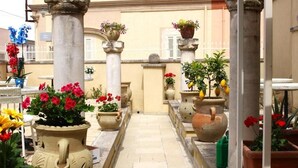 Une cour intérieure avec des colonnes en pierre, des plantes en pot et un sol carrelé.