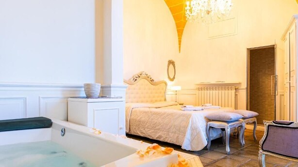 Une pièce avec une baignoire, un lit, une chaise et un lustre.