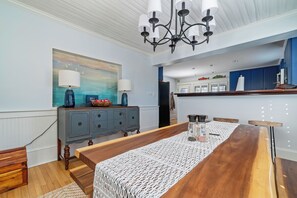 A dining area with a wooden table, a chandelier, a blue cabinet, and a painting on the wall. - Relax at Harbor Watch and enjoy the gorgeous view (Oriental)