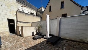 Ein Innenhof mit Steinpflaster, Gartenmöbeln und einer weißen Mauer.
