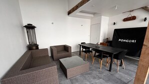 Ein modernes Wohnzimmer mit einer Couch, Hocker und Esstisch.