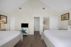A bedroom with two beds, a television on a dresser, and a door leading to another room. - Private Paradise: 3-bedroom Home with Pool and Tropical Backdrop (Duck Key)