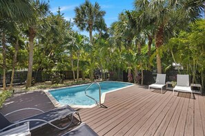 A wooden deck with a swimming pool, lounge chairs, and palm trees. - Private Paradise: 3-bedroom Home with Pool and Tropical Backdrop (Duck Key)