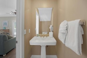 A bathroom with a white sink, a mirror, and a towel rack. - Private Paradise: 3-bedroom Home with Pool and Tropical Backdrop (Duck Key)