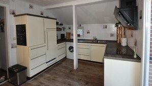 A compact kitchen with white cabinets, a washing machine, and a microwave. - NEW! Villa Totti - Anna's parlor (Neßmersiel)